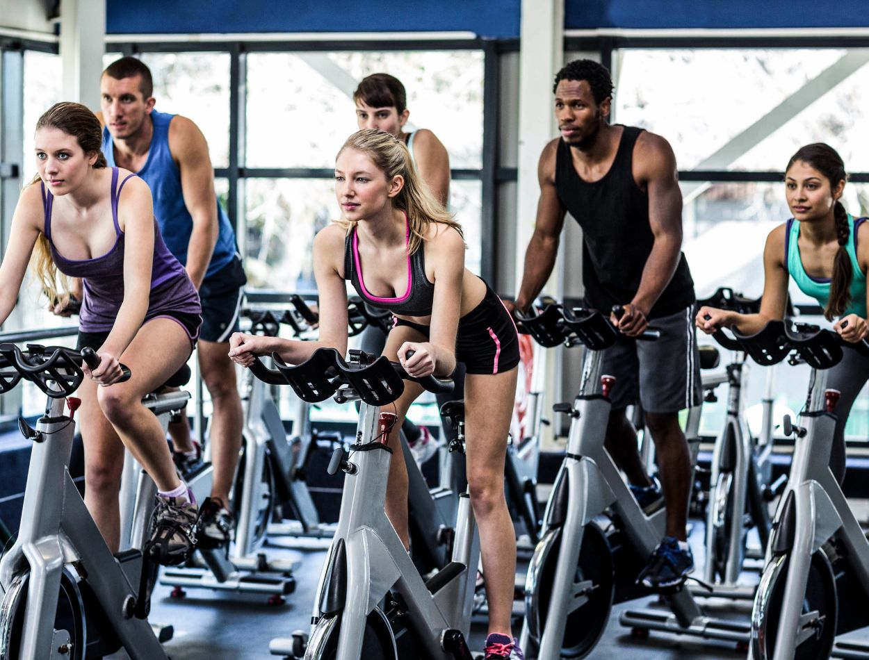 Spinning emagrece mesmo! Conheça mais sobre a modalidade indoor 2 Pessoas praticando spinning em uma academia.