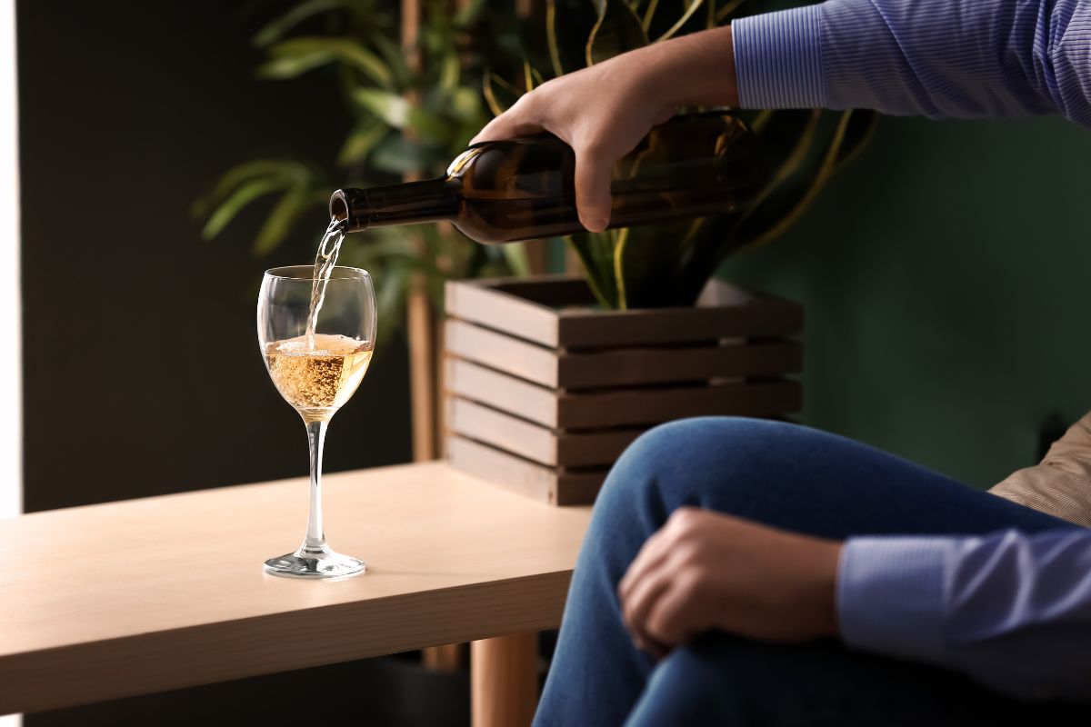 Álcool e coração: por que sua frequência cardíaca aumenta durante o sono 1 pessoa adicionando vinho branco a uma taça.