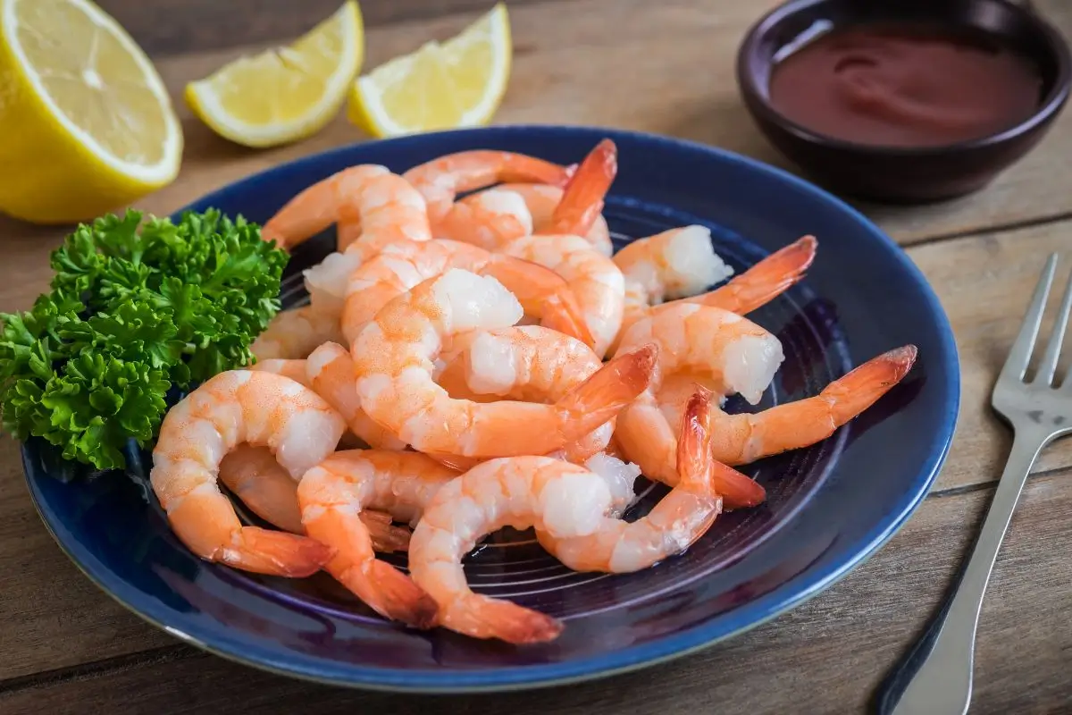 Camarão faz mal para o fígado? Entenda tudo sobre os impactos desse alimento na saúde hepática 1 Prato com camarões, salada e limões.