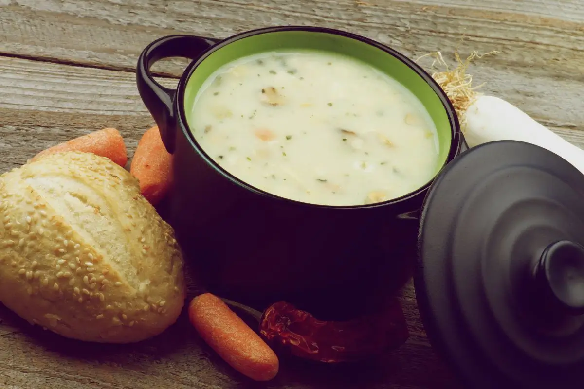 Sopa cremosa de cebola: receita saudável e reconfortante para aquecer o coração 1 Sopa cremosa de cebola em uma panela com pão e cenouras.